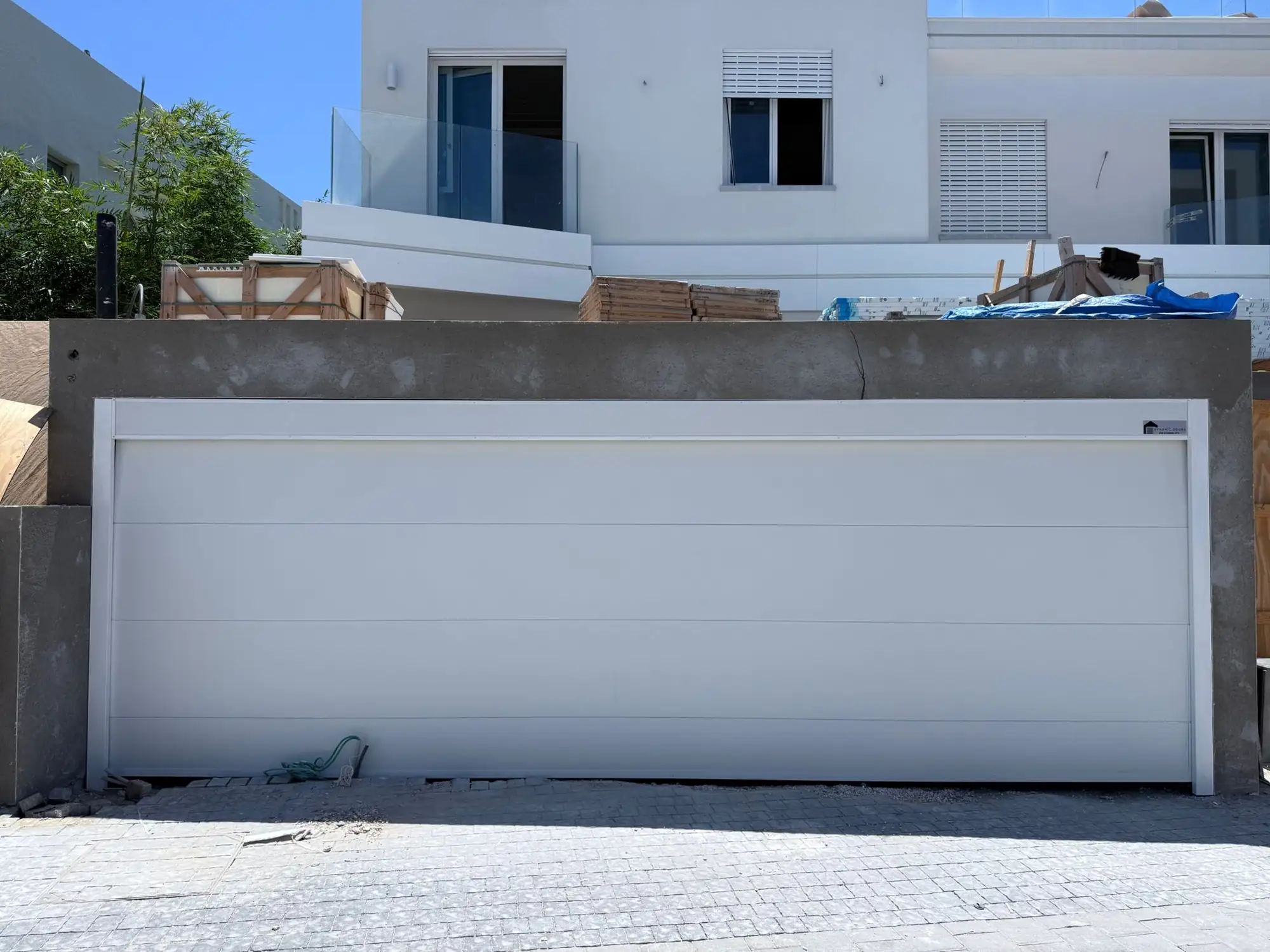 דלת חניה בגימור לבן חלק בעיצוב מינימליסטי למבנה מודרני