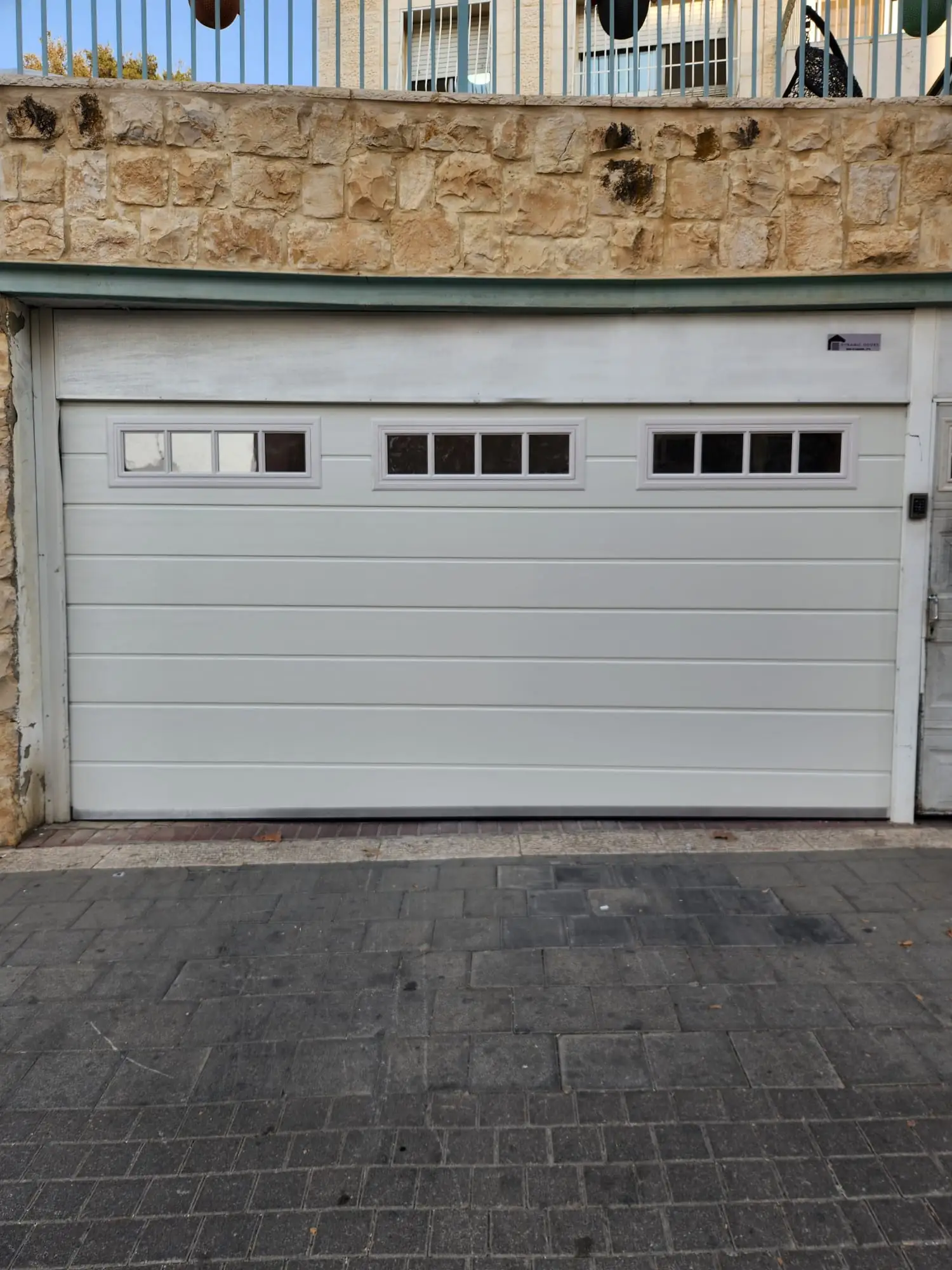 דלת חניה בעיצוב קלאסי עם חלונות עליונים להכנסת אור טבעי